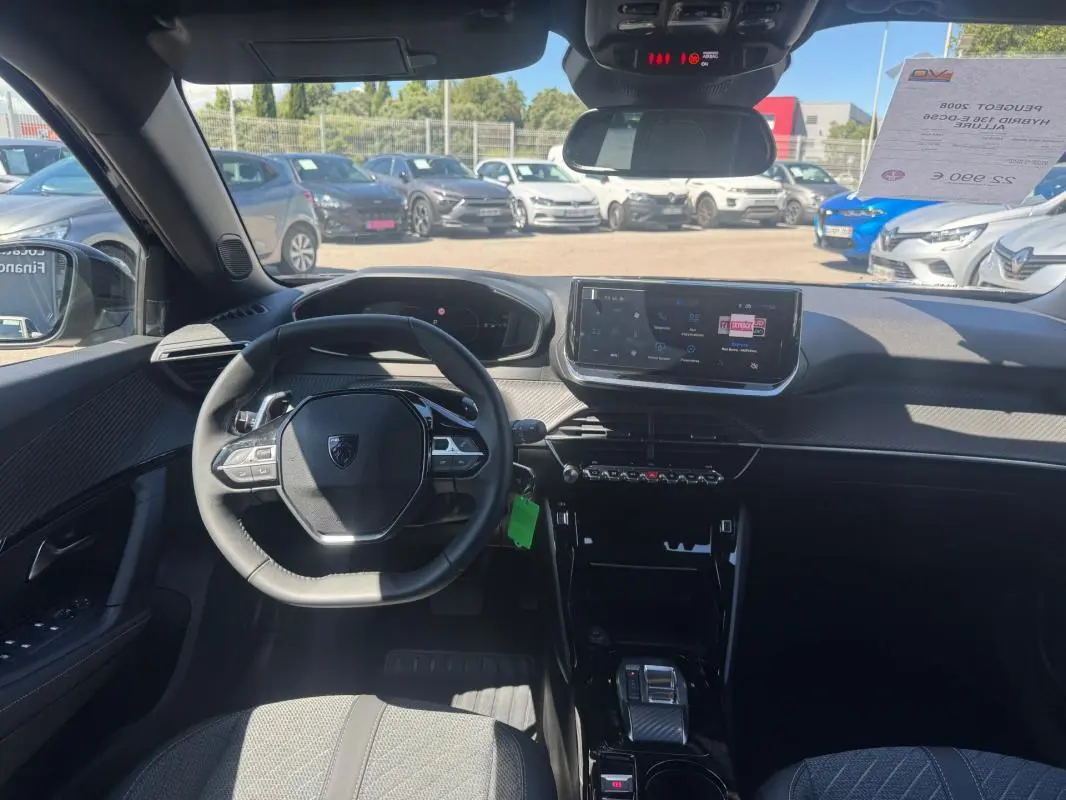 Vue intérieure du tableau de bord et volant du Peugeot 2008 Hybrid 136 e-DCS6 Allure noir avec écran tactile et pack hiver.