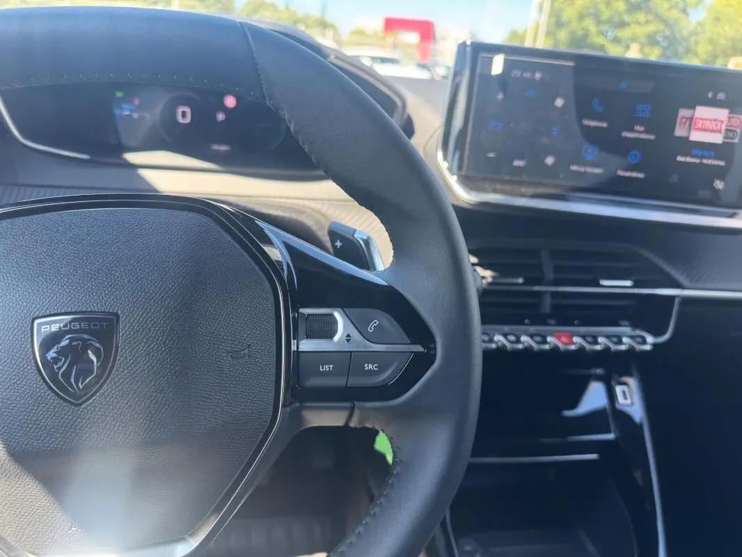 Vue rapprochée du volant noir de la Peugeot 2008 Hybrid 136 e-DCS6 Allure avec tableau de bord numérique et écran tactile.