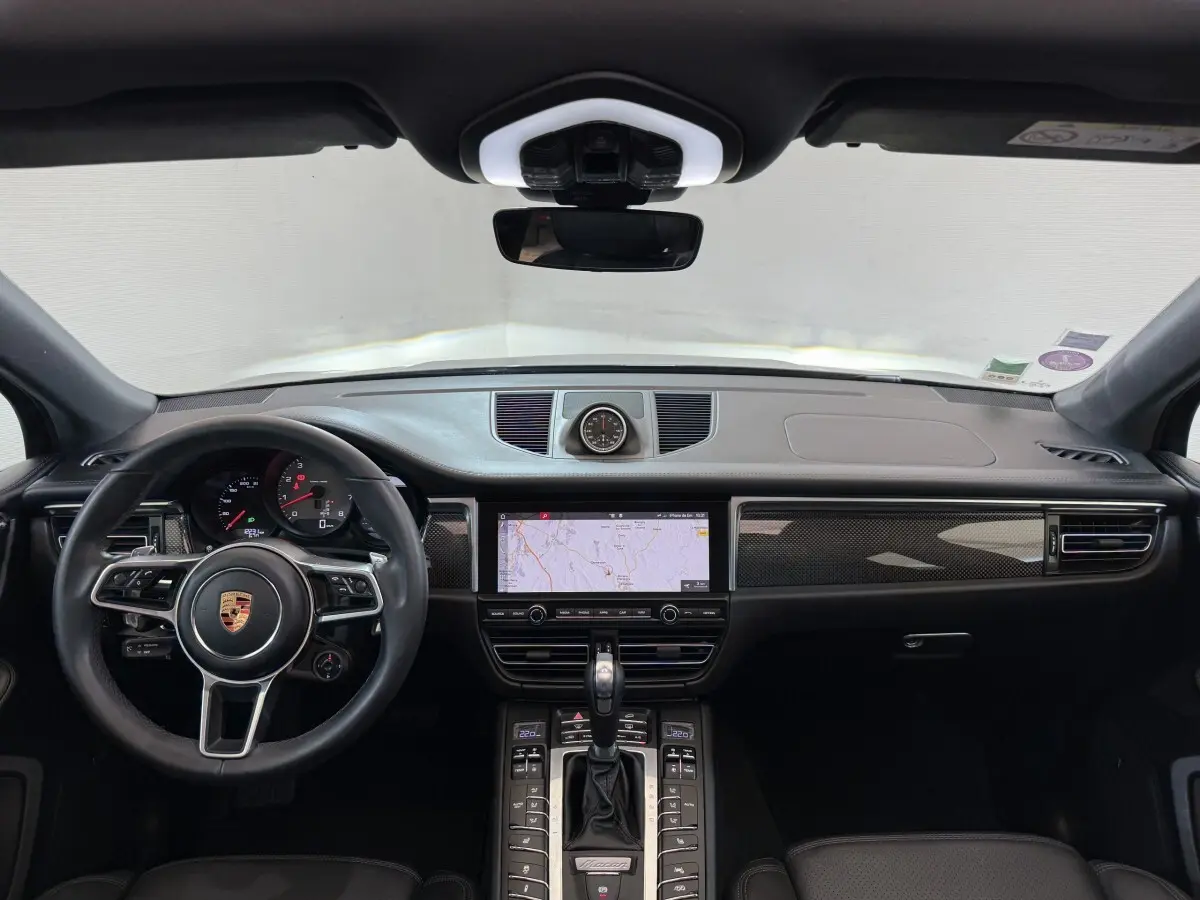 Vue intérieure frontale du tableau de bord noir du Porsche Macan 3.0 S avec volant cuir alu et écran tactile central.