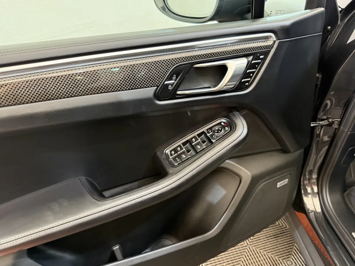 Vue rapprochée de la porte avant gauche du Porsche Macan 3.0 S gris foncé avec garniture carbone et commandes électriques.