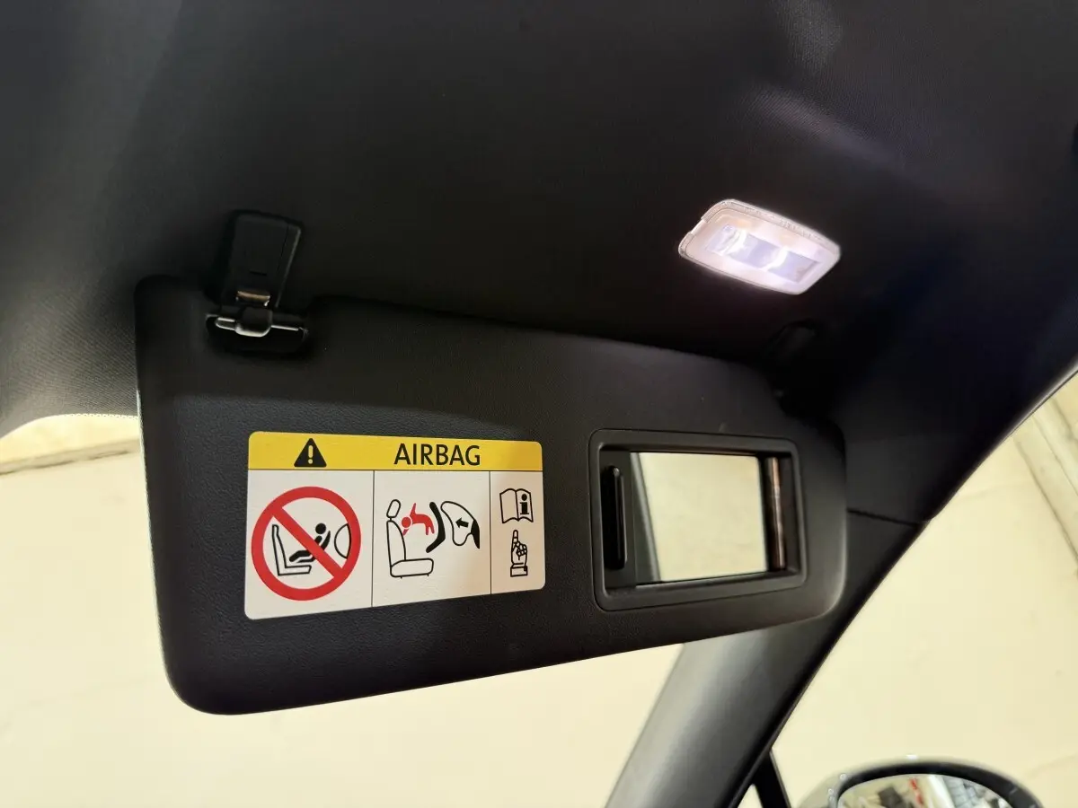 Détail du pare-soleil côté conducteur avec miroir et avertissement airbag dans un Porsche Macan gris foncé.