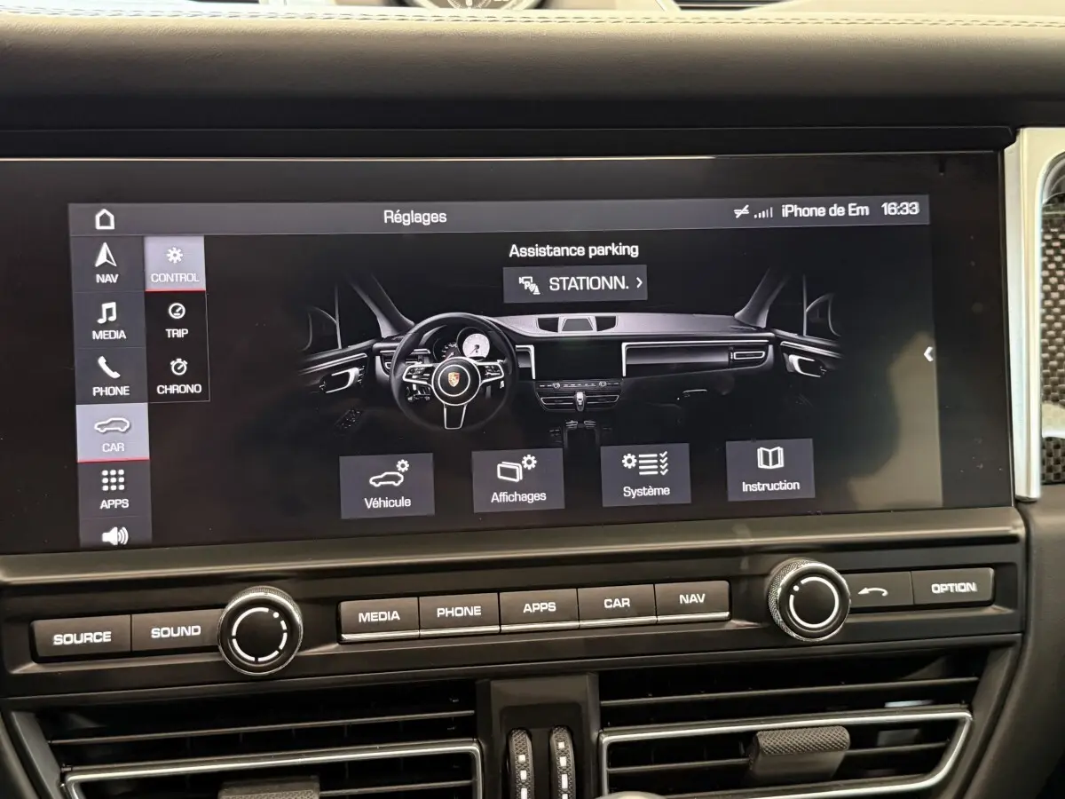 Vue rapprochée de l’écran tactile central du tableau de bord du Porsche Macan 3.0 S gris foncé, affichant les réglages d’assistance parking.