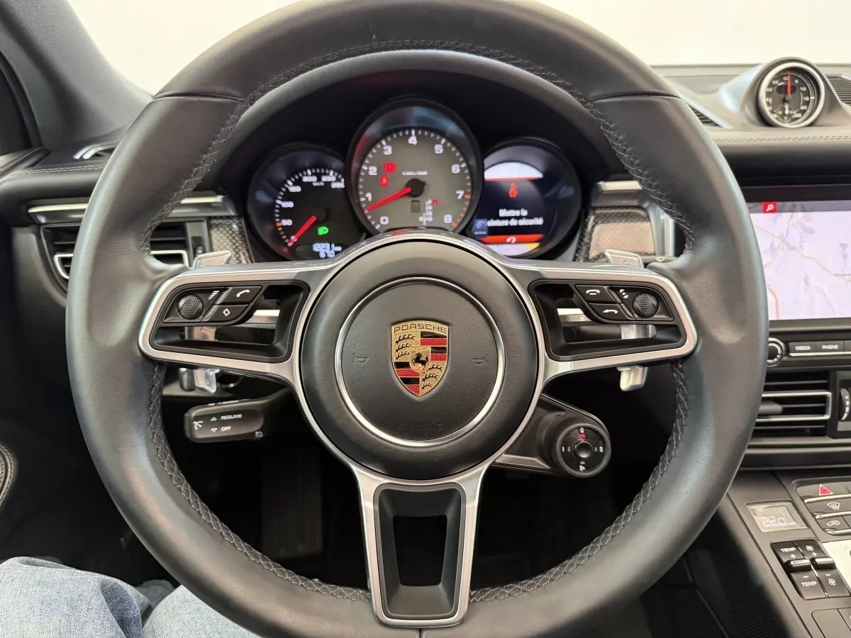 Vue rapprochée du volant cuir et alu multifonctions du Porsche Macan 3.0 S avec tableau de bord et écran tactile visible.
