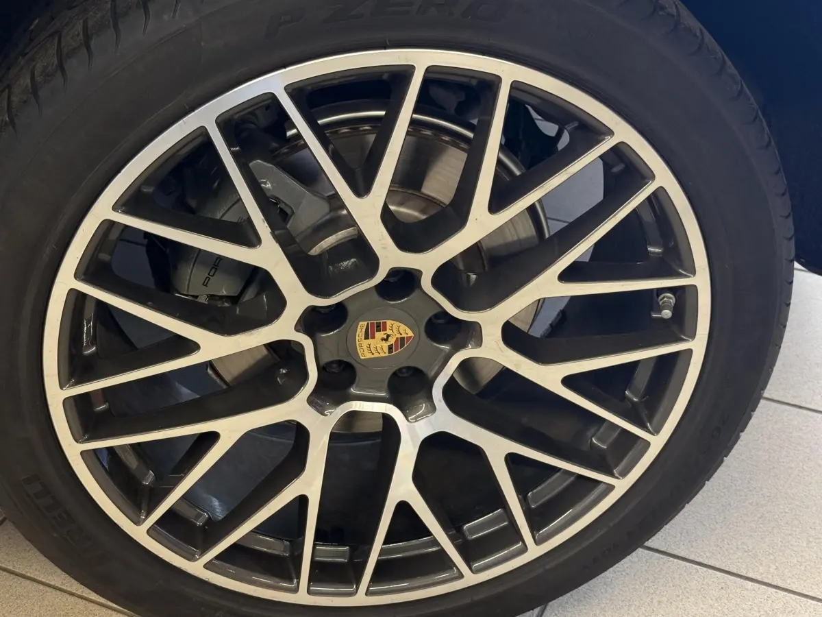Gros plan sur la jante alliage bicolore avec logo Porsche du SUV gris foncé Porsche Macan 3.0 S 2019.