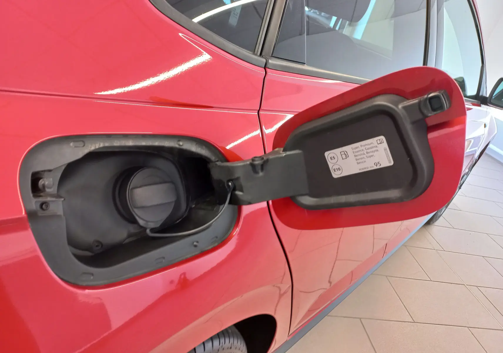 Vue rapprochée du côté gauche arrière d’une Volkswagen Polo Rouge Roi 2025 avec trappe à carburant ouverte.