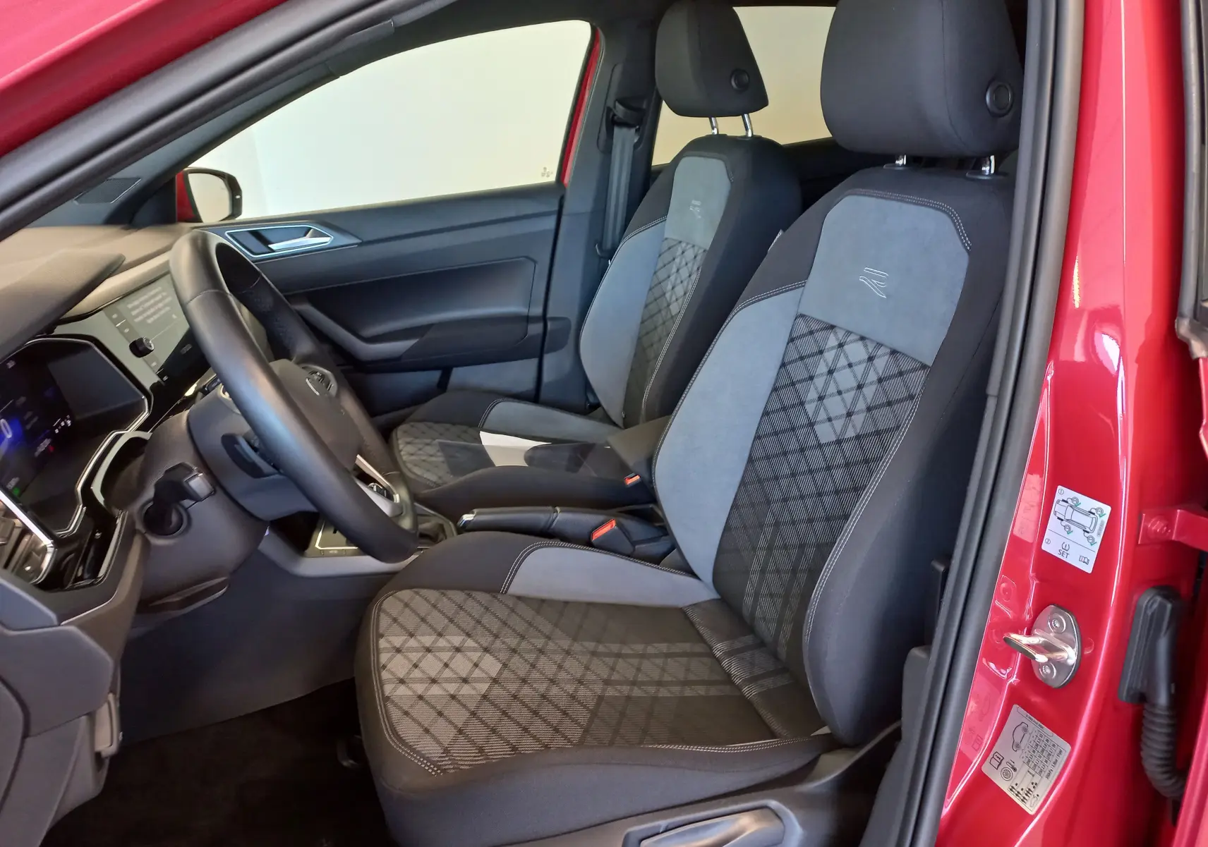Vue intérieure côté conducteur de la Volkswagen Polo 2025 Rouge Roi avec sièges R-Line en tissu et alcantara.
