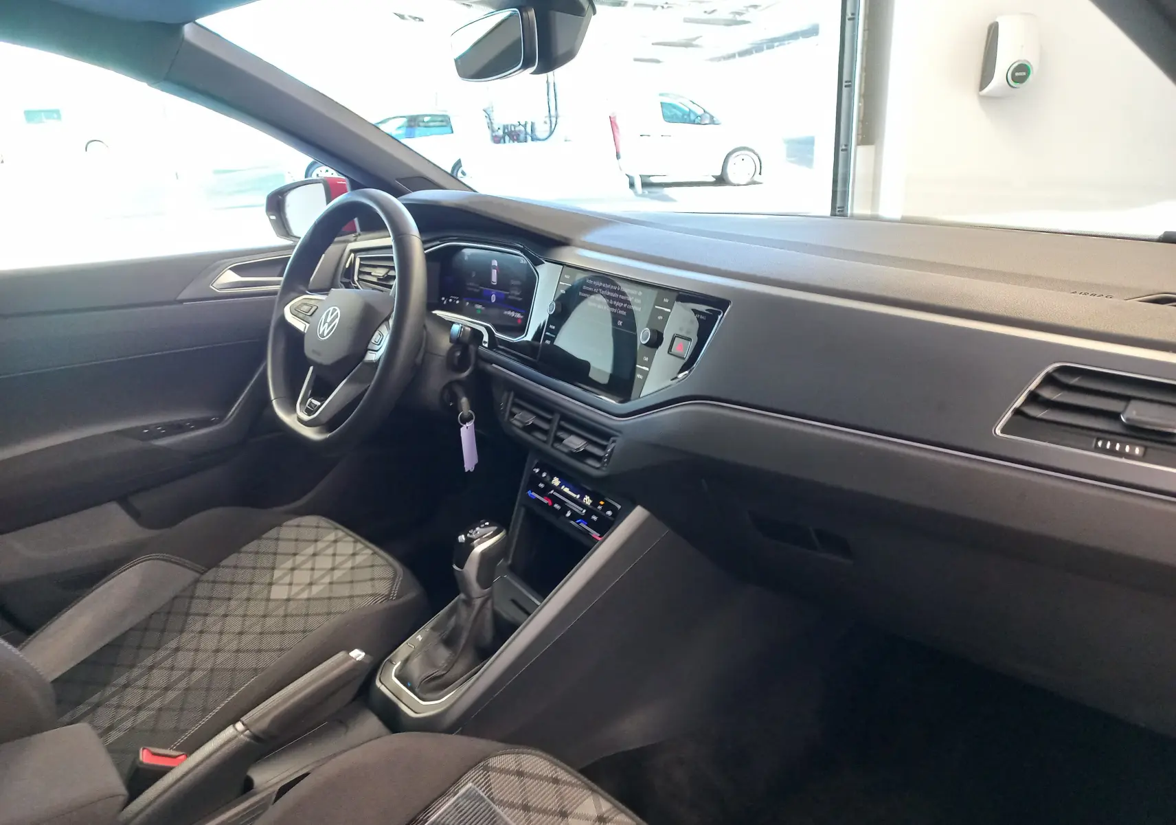 Vue intérieure côté conducteur de la Volkswagen Polo 2025 Rouge Roi, avec tableau de bord numérique et console centrale moderne.