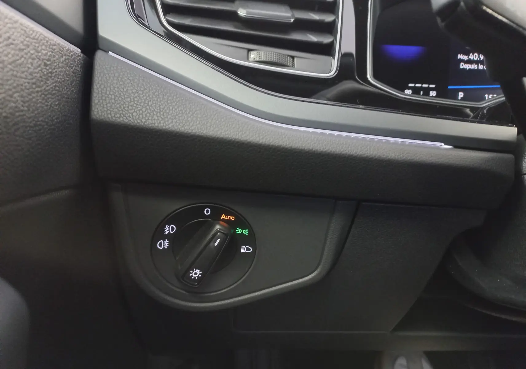 Détail de l'intérieur côté gauche du tableau de bord de la Volkswagen Polo Rouge Roi 2025, avec commande d'éclairage en mode automatique.