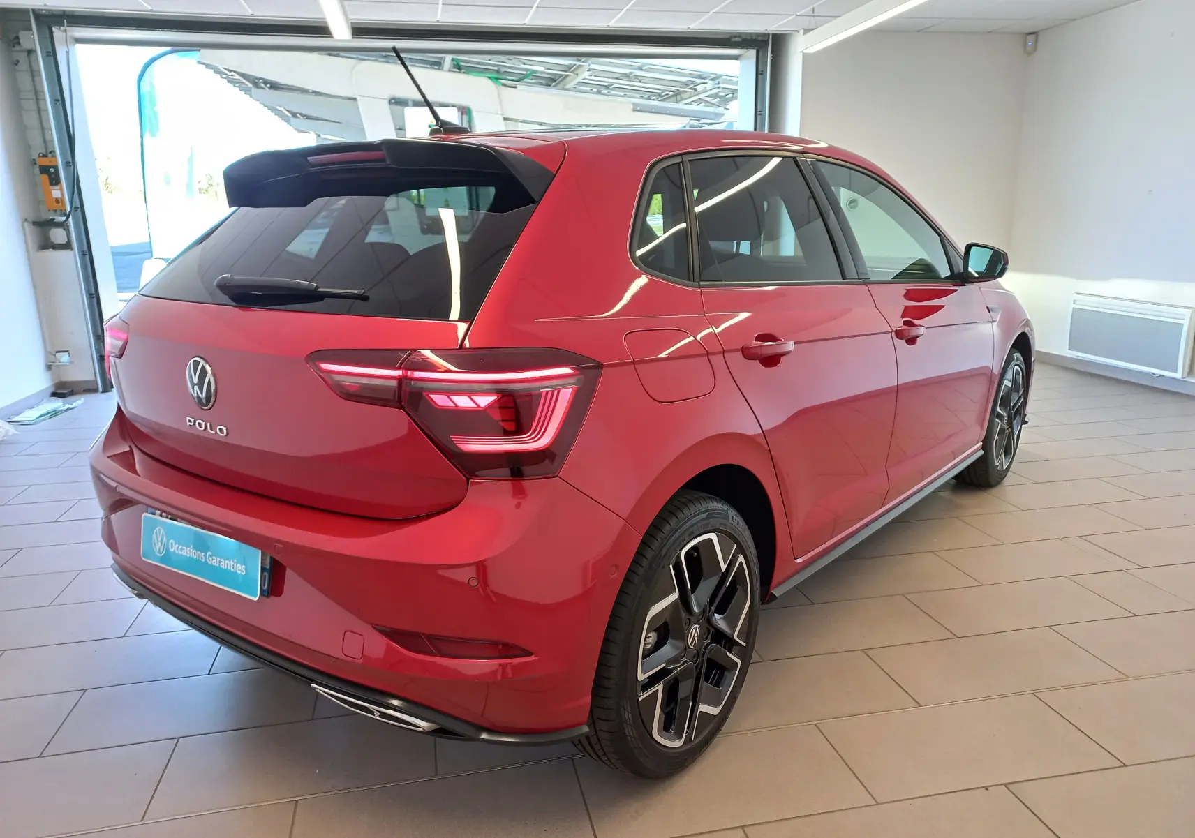 Volkswagen Polo 2025 Rouge Roi vue 3/4 arrière droit, feux LED allumés et jantes R-Line distinctives.