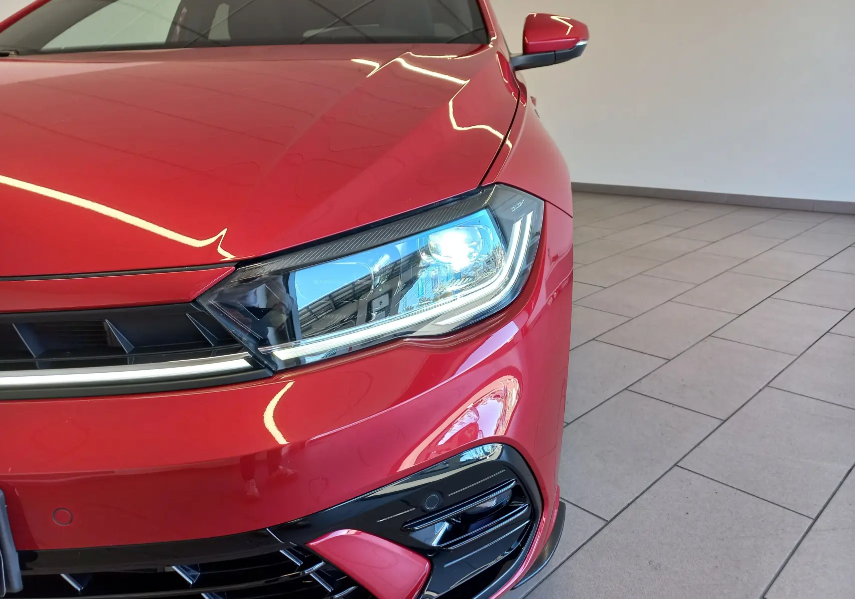 Gros plan sur l'avant droit de la Volkswagen Polo Rouge Roi 2025, mettant en valeur son phare LED et la calandre R-Line.