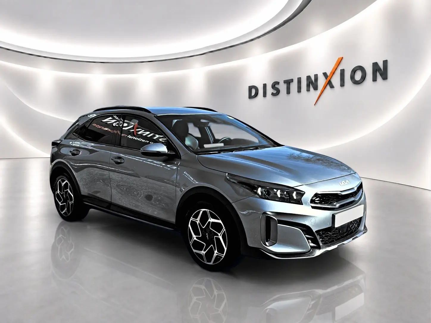 Kia Xceed gris en vue 3/4 avant droit, avec jantes alu et calandre chromée dans un showroom lumineux.