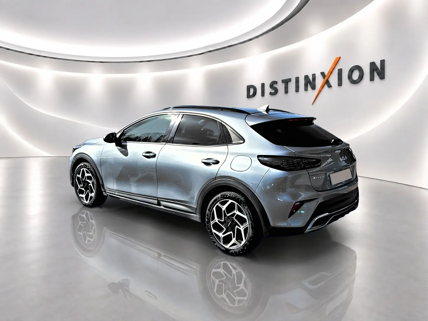 KIA Xceed gris 3/4 arrière droit en showroom avec jantes alu au design hexagonal et vitres surteintées.