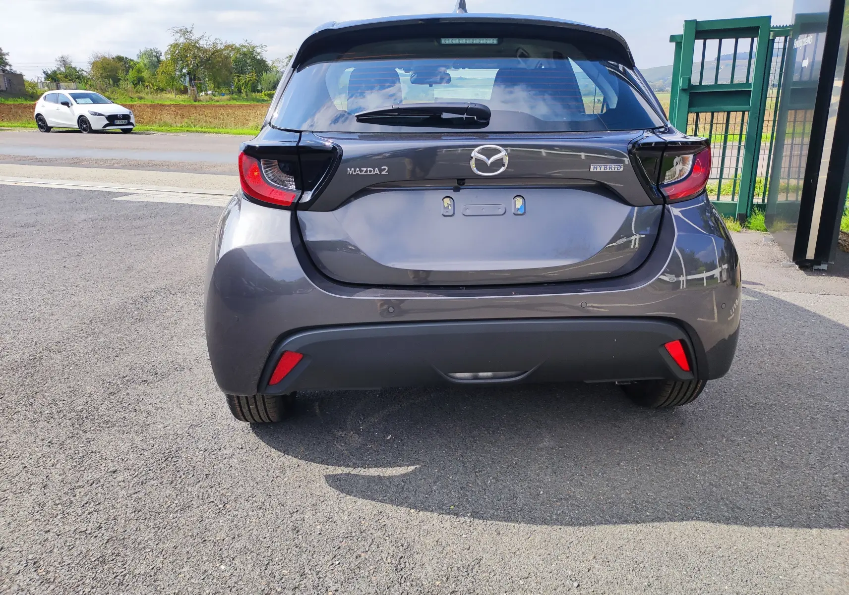 Vue arrière d'une Mazda2 gris foncé 2024 hybride, avec logo Mazda et badge Hybrid bien visibles sur le hayon.