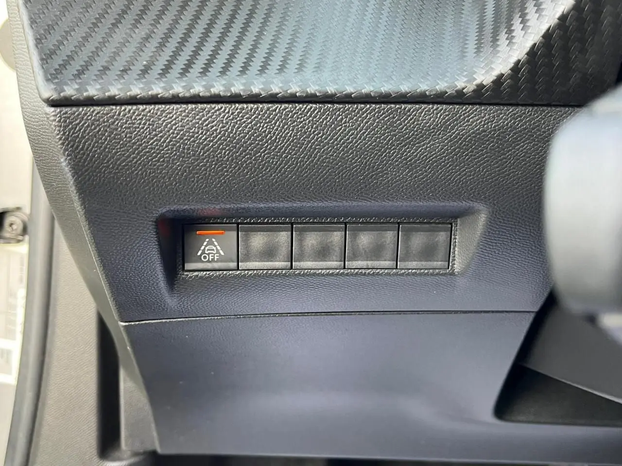 Bouton de désactivation de l'assistance au maintien de voie sur le tableau de bord d'une Peugeot 2008 gris Artense toit noir.