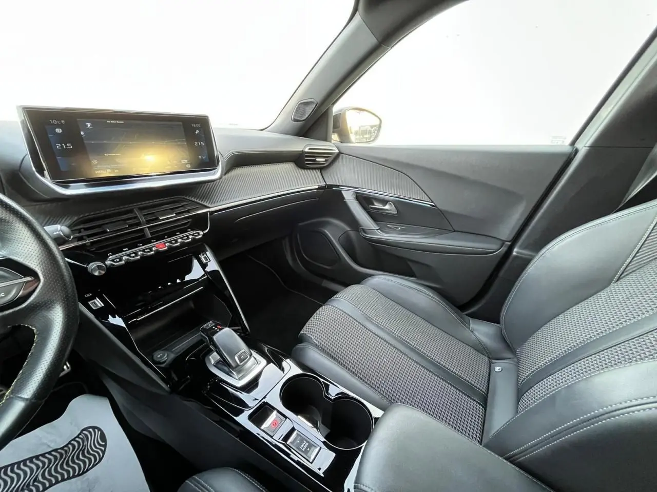 Intérieur avant droit du Peugeot 2008 II gris, avec tableau de bord numérique et console centrale brillante noire.