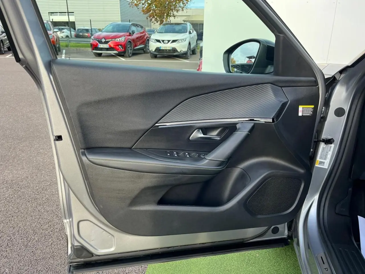 Gros plan sur la porte avant gauche gris Artense du Peugeot 2008 II, avec garniture noire et insert effet carbone.