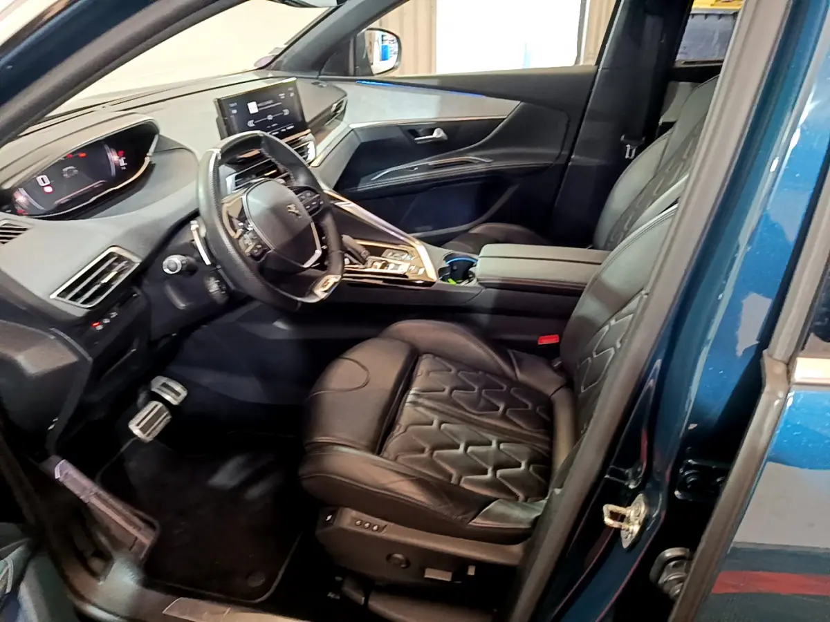 Vue intérieure côté conducteur du Peugeot 5008 bleu 2021, sièges cuir noirs et tableau de bord digital moderne