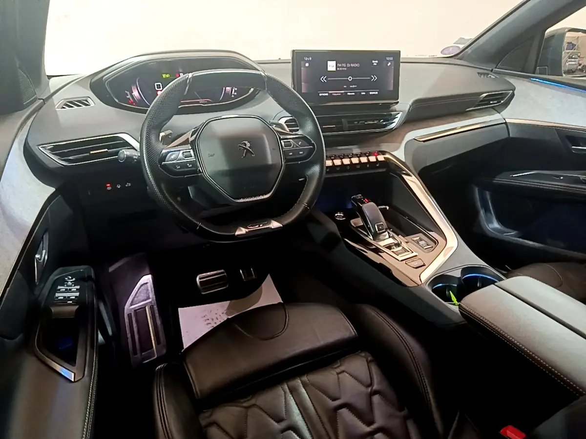 Intérieur Peugeot 5008 GT 2021 vu côté conducteur, volant compact, écran tactile central et sellerie cuir noire.