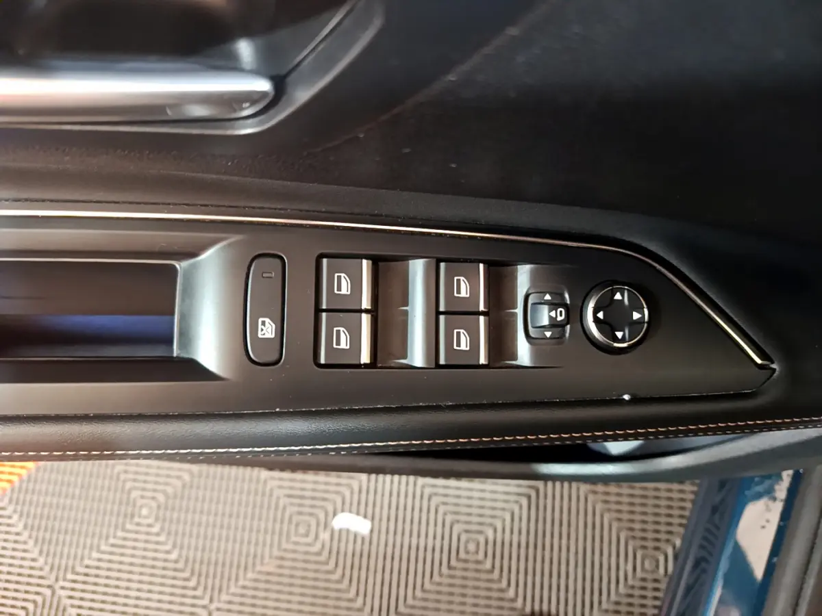 Commande des vitres et rétroviseurs côté gauche en cuir noir avec surpiqûres sur Peugeot 5008 bleu, vue intérieure rapprochée.