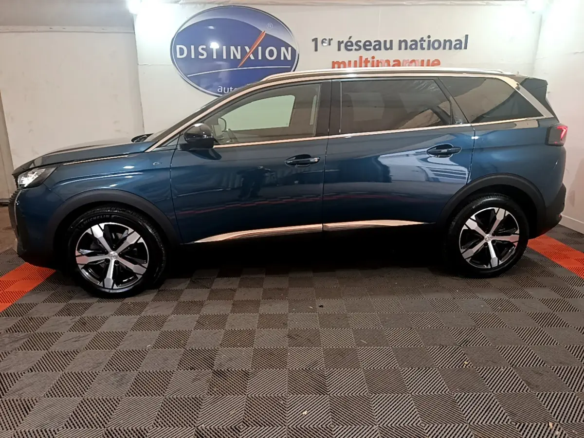 Profil côté gauche du Peugeot 5008 bleu 2021 avec jantes alliage et toit noir en intérieur showroom