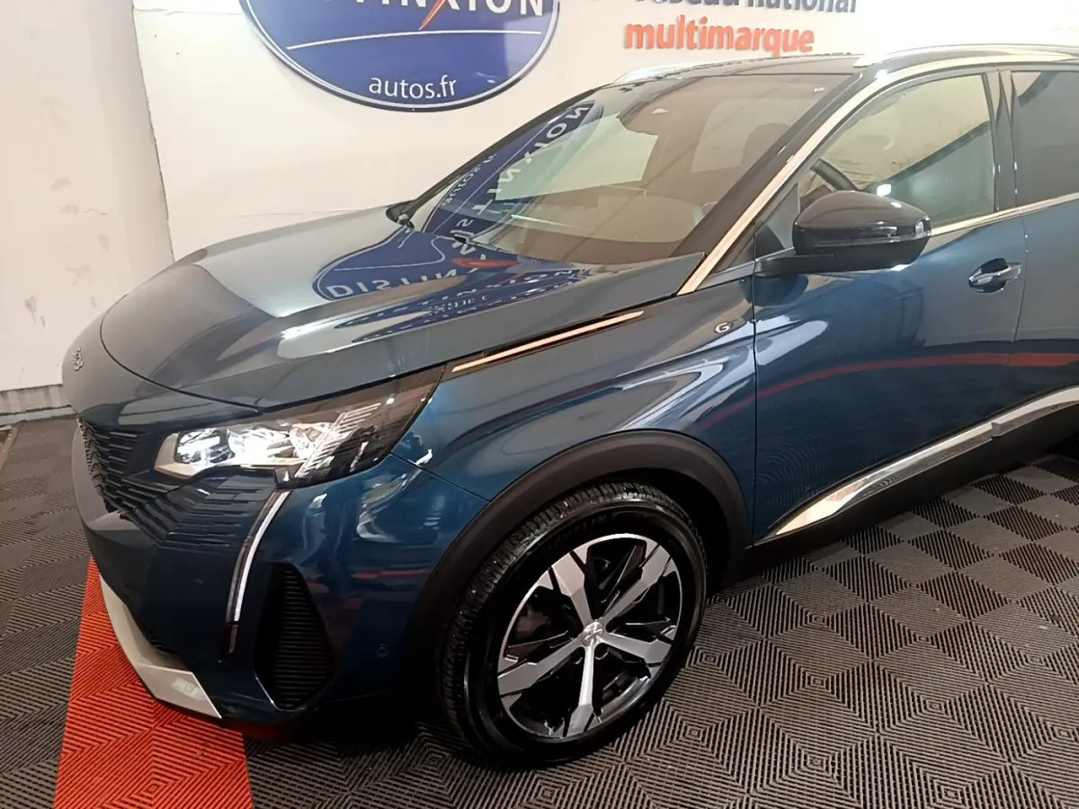 Vue 3/4 avant droit d'un Peugeot 5008 bleu avec phares LED et jantes alliage bicolores.