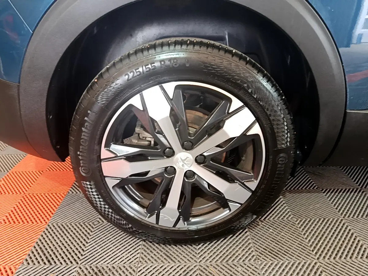 Gros plan sur la roue avant droite du Peugeot 5008 bleu, mettant en valeur la jante alliage bicolore et le pneu Continental.