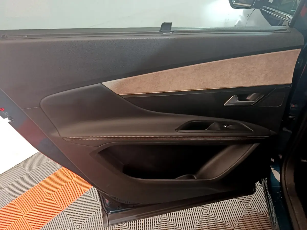 Vue intérieure côté gauche de la porte arrière du Peugeot 5008 bleu, avec garniture noire et beige élégante.