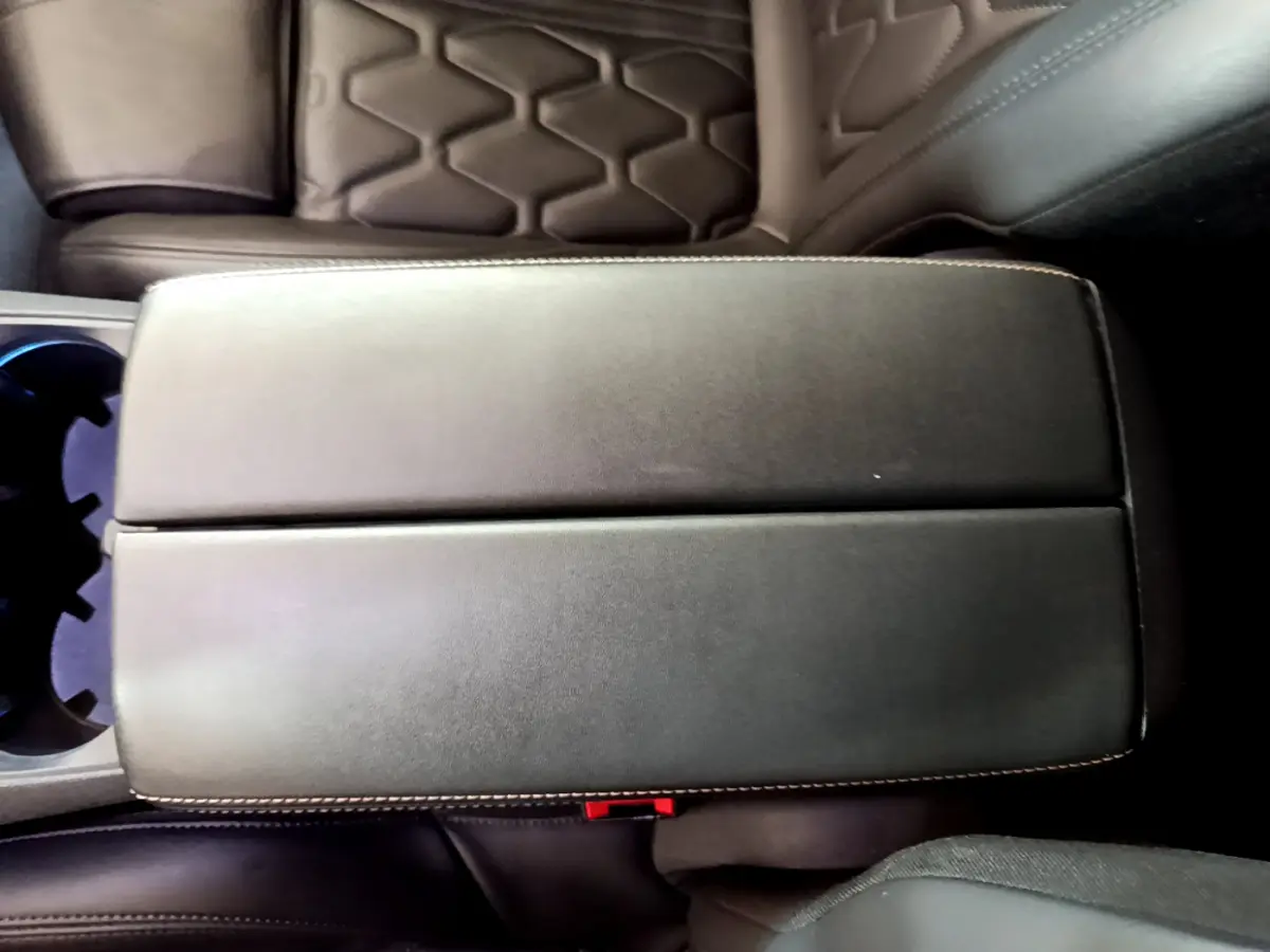 Vue rapprochée de l'accoudoir central en cuir noir avec surpiqûres blanches dans un Peugeot 5008 GT bleu.