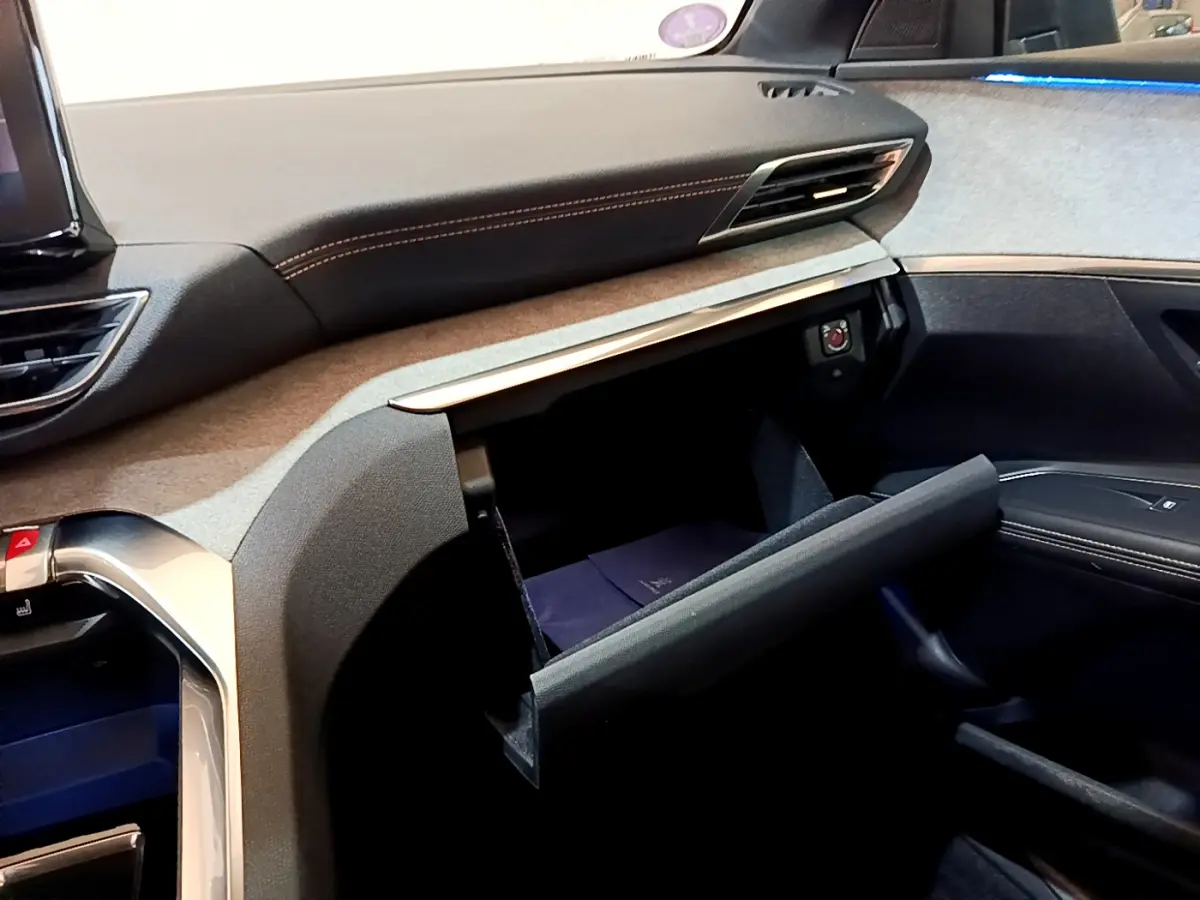 Intérieur du Peugeot 5008 GT 2021, vue côté passager sur la boîte à gants ouverte et tableau de bord noir et gris.