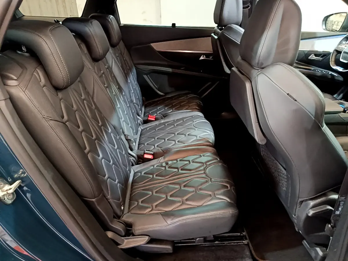 Vue latérale intérieure des sièges arrière en cuir noir du Peugeot 5008 GT bleu, avec motifs géométriques et appuie-têtes.