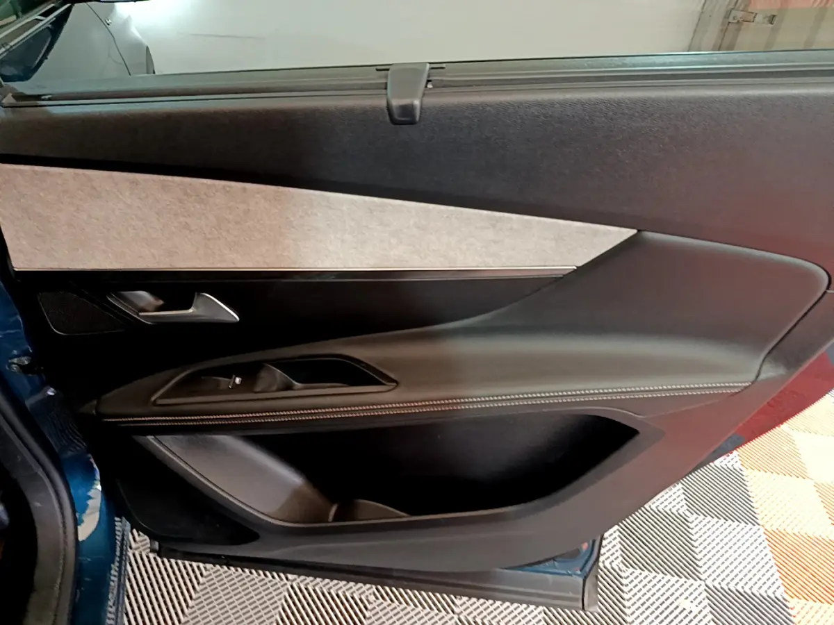 Porte intérieure côté gauche du Peugeot 5008 GT bleu 2021, avec garniture noire et surpiqûres blanches.