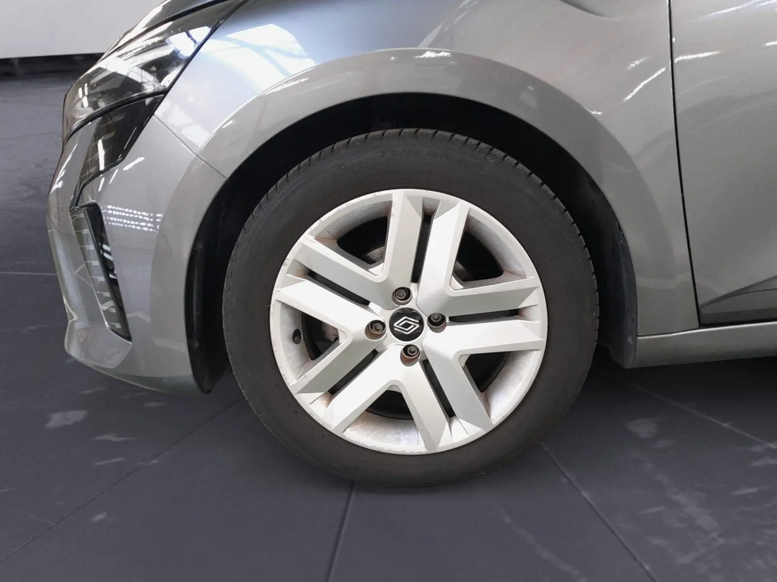 Gros plan sur la roue avant gauche d'une Renault Clio V gris schiste avec jante alliage à cinq branches.