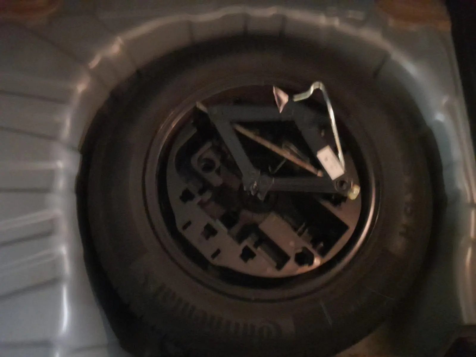 Gros plan sur la roue de secours en tôle noire dans le coffre d'une Renault Clio V gris schiste.