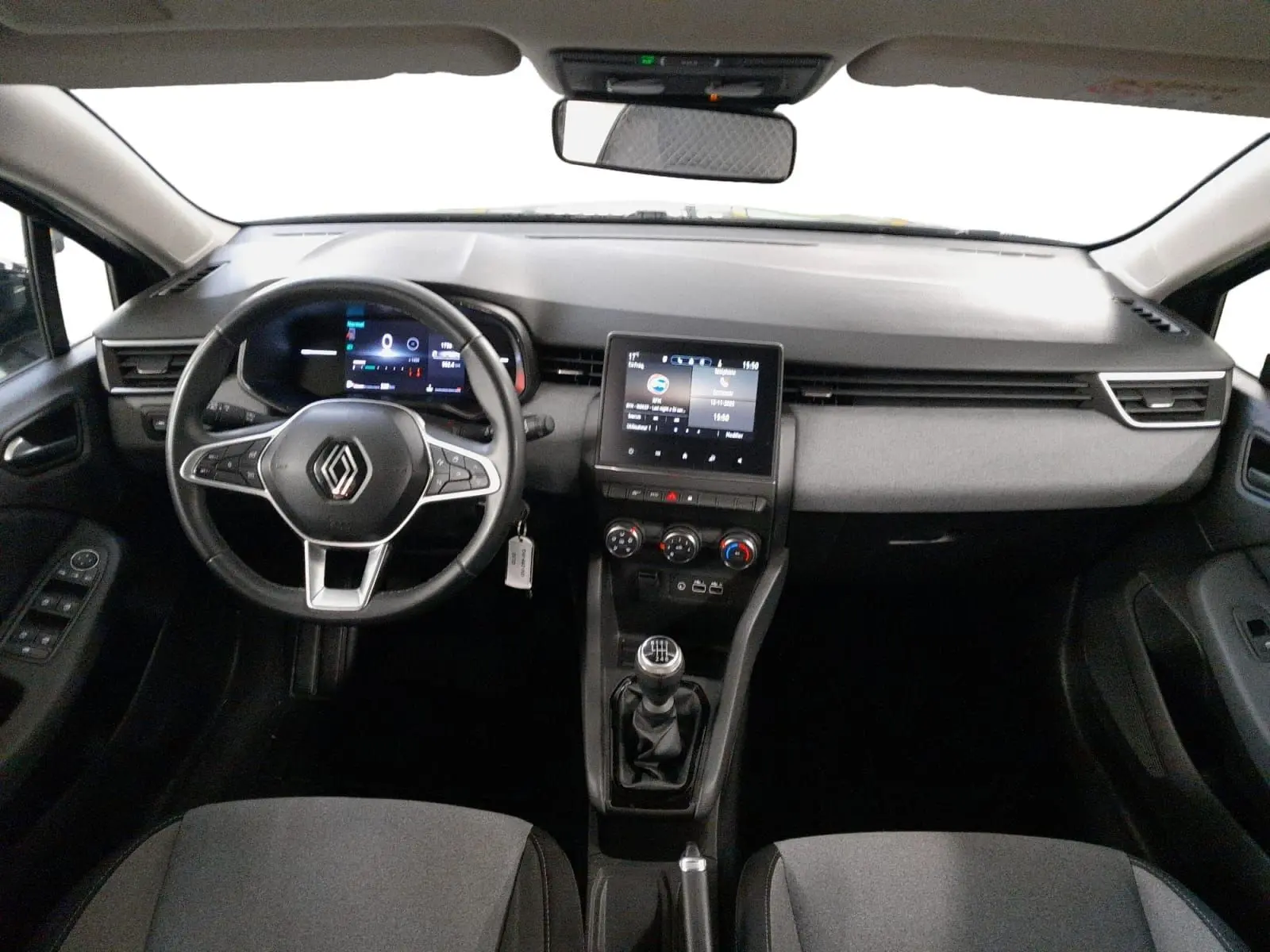 Vue intérieure avant de la Renault Clio V gris schiste, tableau de bord numérique et console centrale avec boîte manuelle.