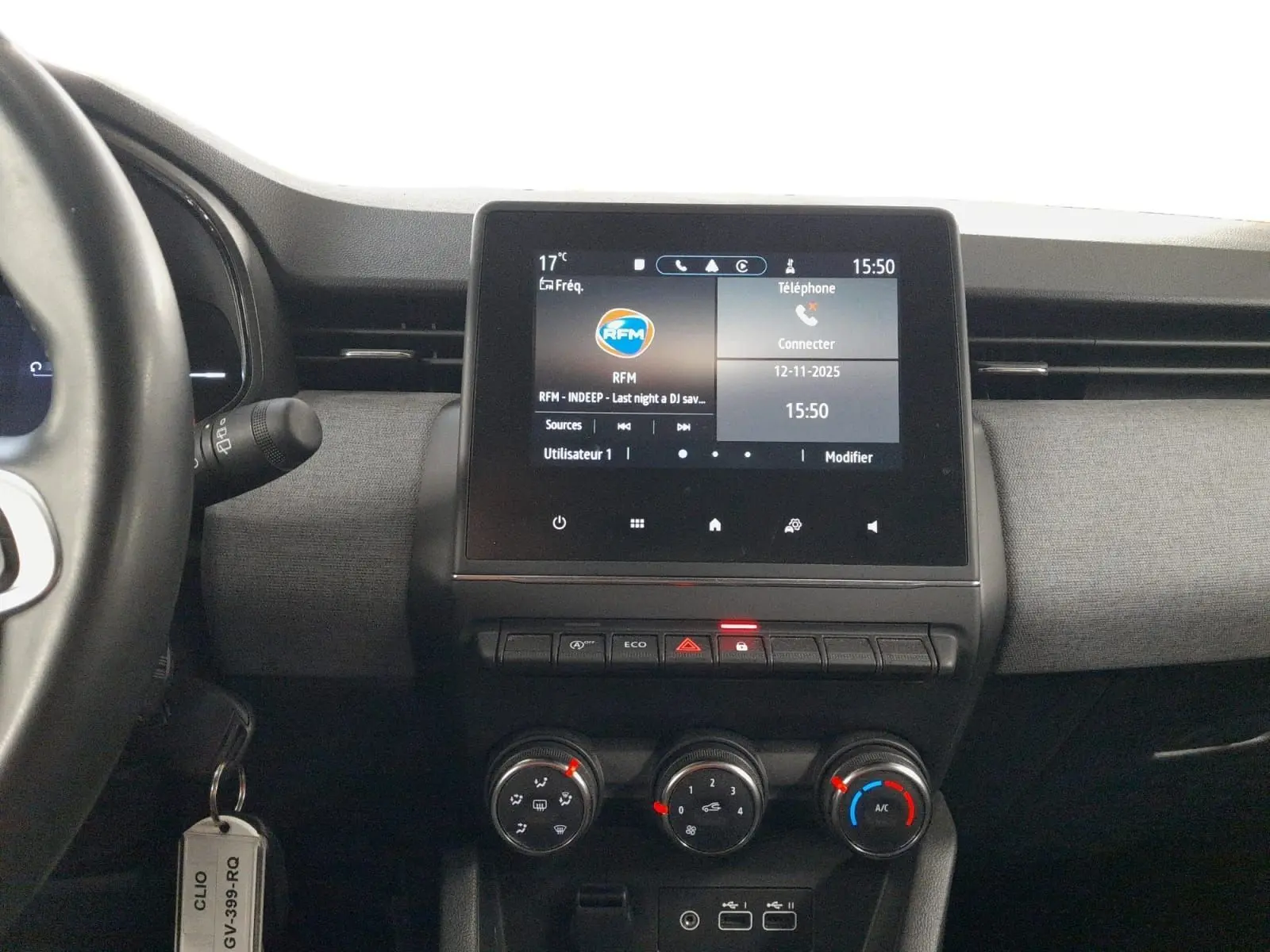 Vue intérieure du tableau de bord de la Renault Clio V PH2 TCE 90 Evolution avec écran tactile et commandes manuelles de climatisation.