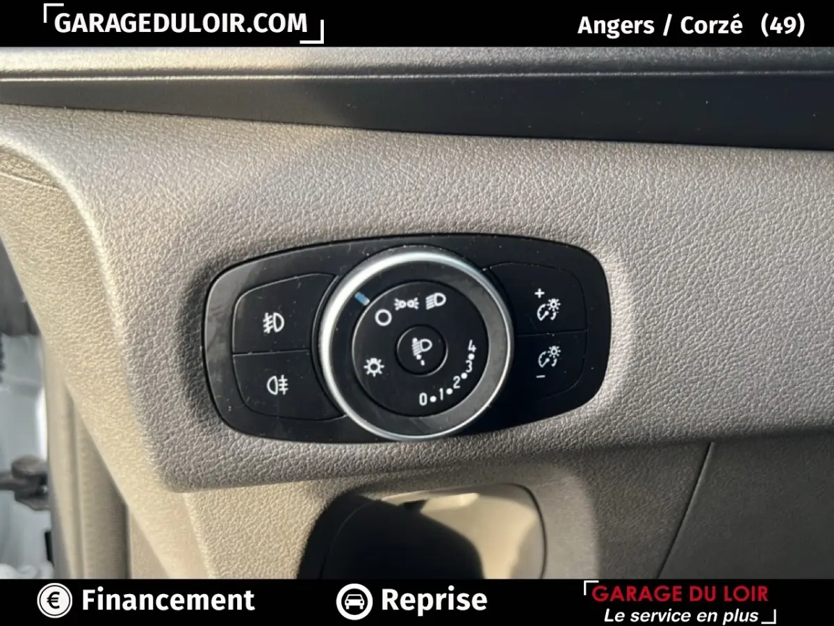 Gros plan sur le bouton de réglage des phares dans l’habitacle du Ford Transit Custom blanc, côté conducteur.