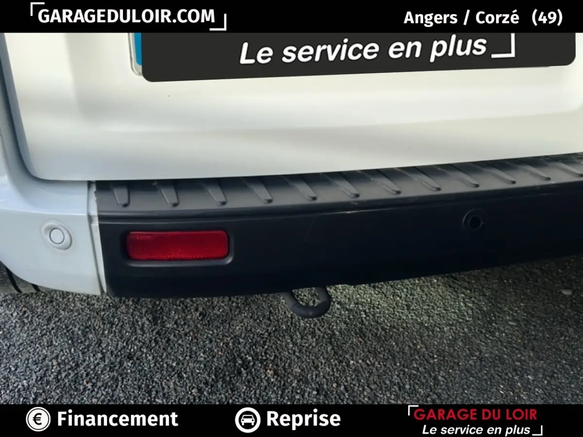 Gros plan sur le pare-chocs arrière noir et la partie basse blanche du Ford Transit Custom Fourgon blanc, avec feu rouge et crochet d’attelage visible.