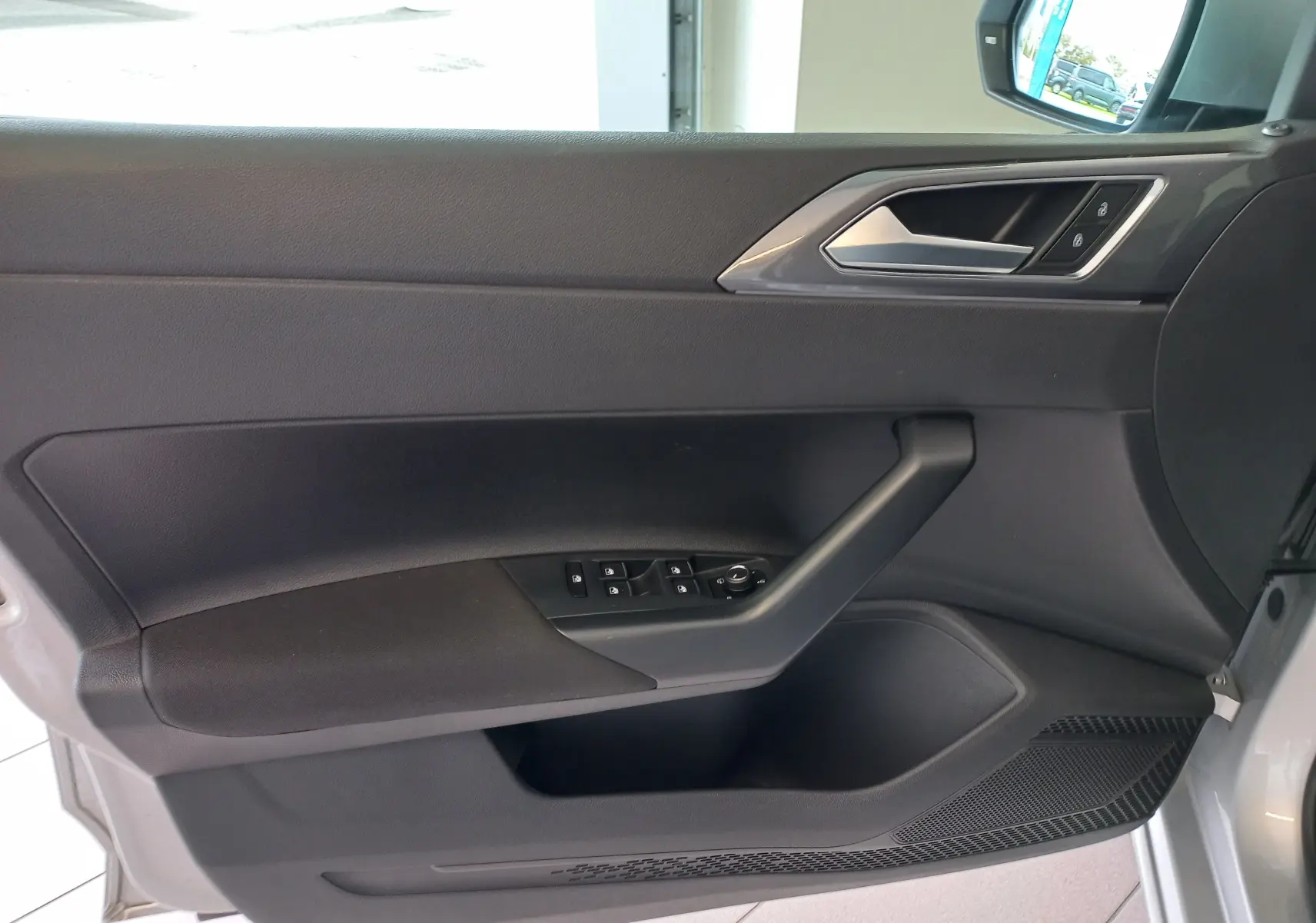 Vue intérieure côté gauche de la porte avant d'une Volkswagen Polo 2026 couleur reflet d'argent avec commandes de vitres et serrure.