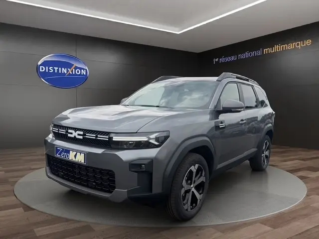 Vue 3/4 avant du Dacia Bigster gris foncé, avec calandre noire distinctive et jantes bicolores modernes.