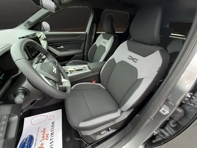 Vue intérieure côté conducteur du Dacia Bigster Journey Hybrid 155 2026, sièges bi-ton gris et noir avec logo XC brodé.
