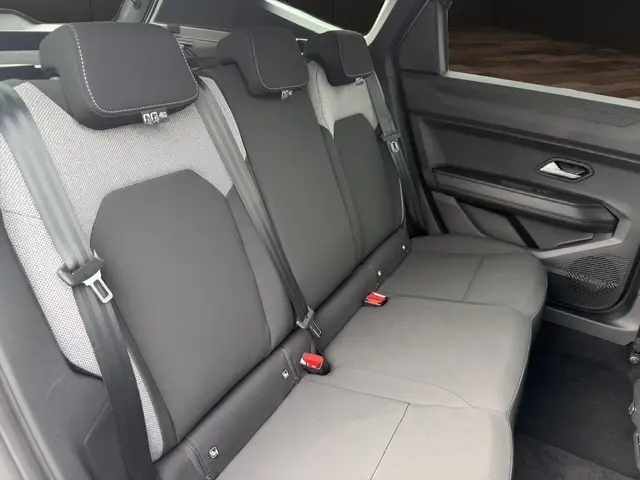 Vue latérale droite de la banquette arrière gris foncé du Dacia Bigster Journey Hybrid 155 avec ceintures et appuie-têtes intégrés.