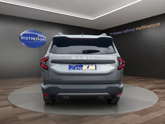 Vue arrière d'un Dacia Bigster gris foncé avec logo DACIA lumineux et feux arrière en forme de C.