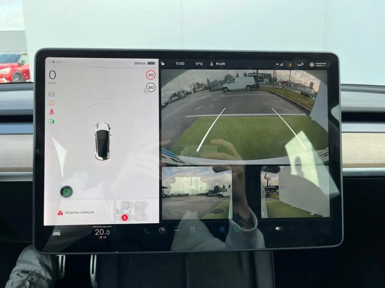 Écran tactile intérieur de Tesla Model 3 blanc 2022 montrant la caméra de recul et l'affichage des capteurs de stationnement.