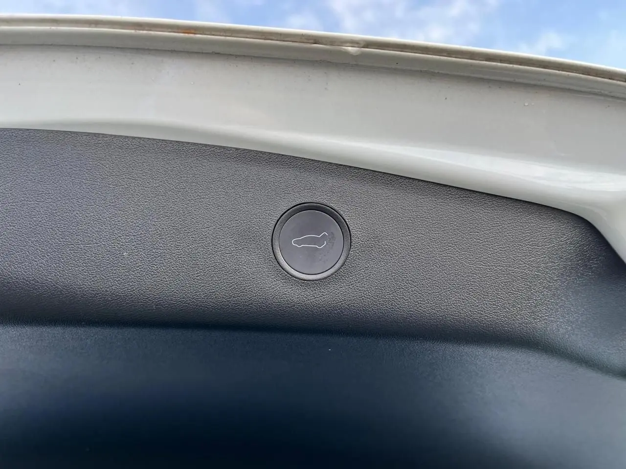 Bouton de déverrouillage du coffre intégré sur la partie intérieure du hayon blanc d'une Tesla Model 3 Standard Plus 2022.