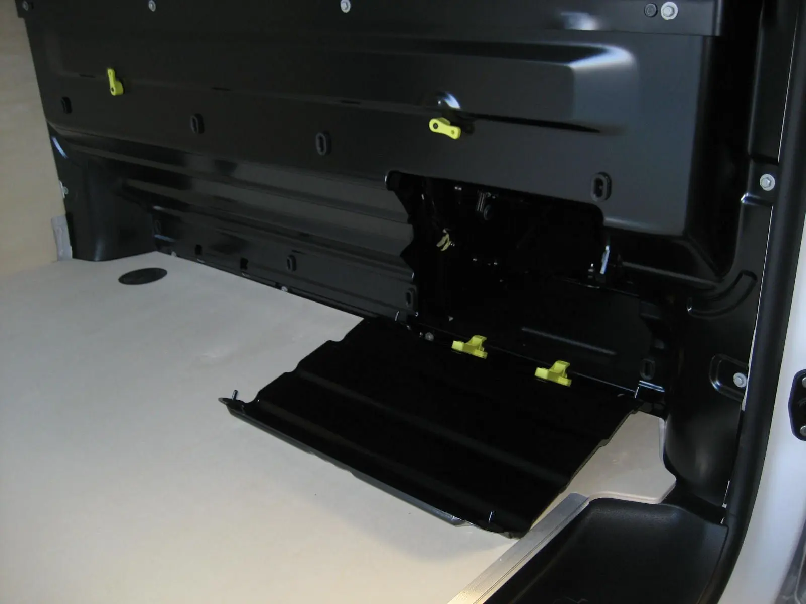 Détail intérieur du coffre du Peugeot Expert Fourgon blanc 2025, avec trappe noire ouverte et plancher bois clair.