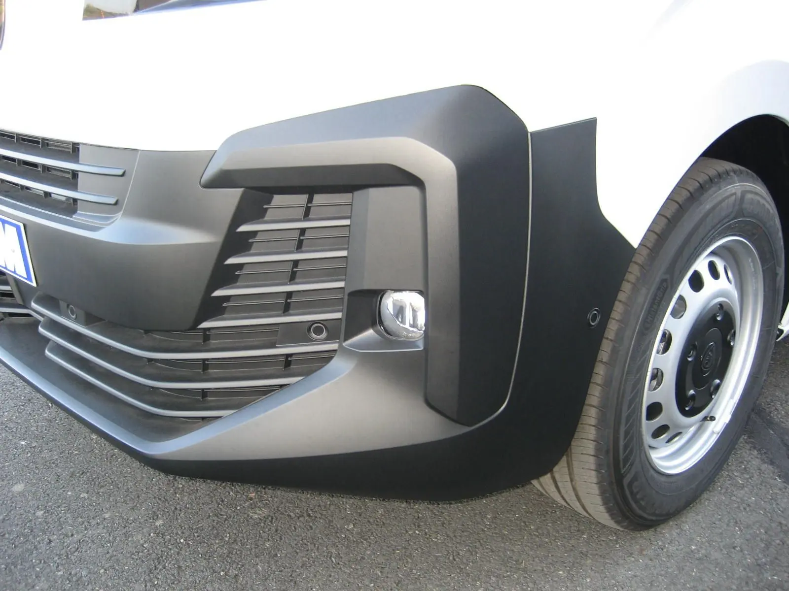 Gros plan sur le pare-chocs avant droit blanc du Peugeot Expert Fourgon avec antibrouillard et jante acier.