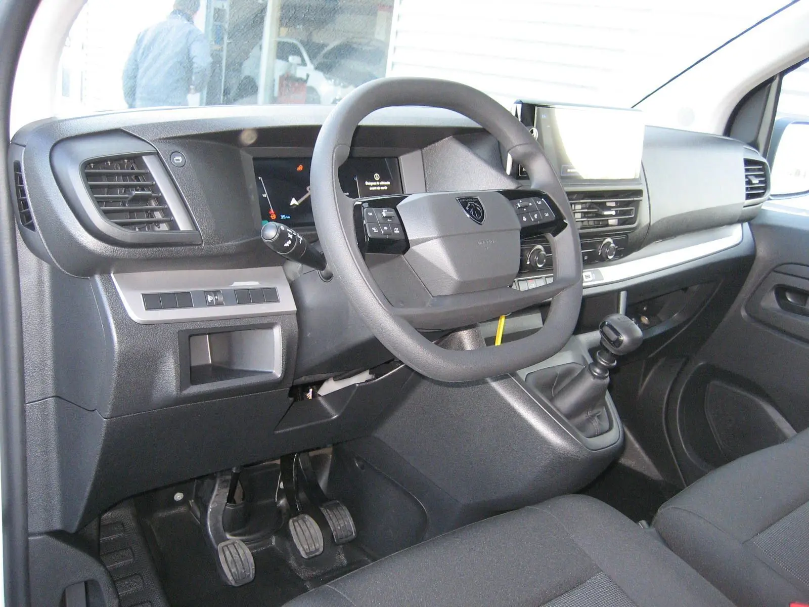 Vue intérieure côté conducteur du Peugeot Expert Fourgon blanc 2025, volant multifonction et boîte manuelle visibles.