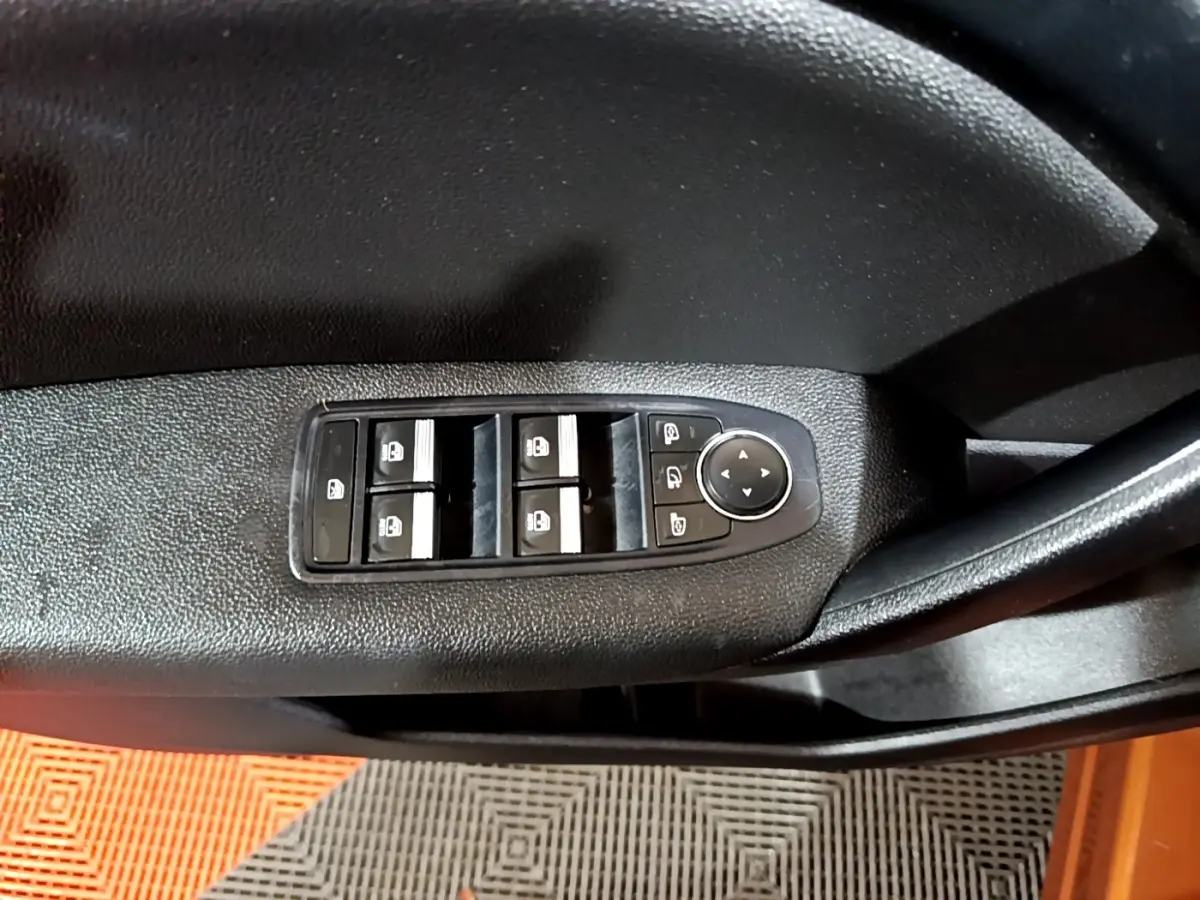 Gros plan sur les commandes de lève-vitres et rétroviseurs côté conducteur d’un Renault Captur jaune.