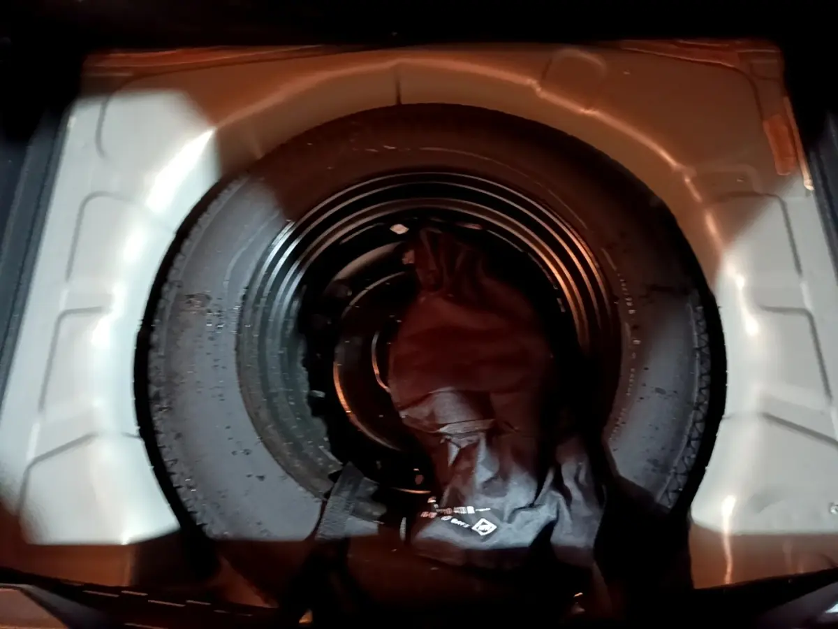 Gros plan sur la roue de secours noire logée dans le coffre du Renault Captur jaune, version Intens 2020.