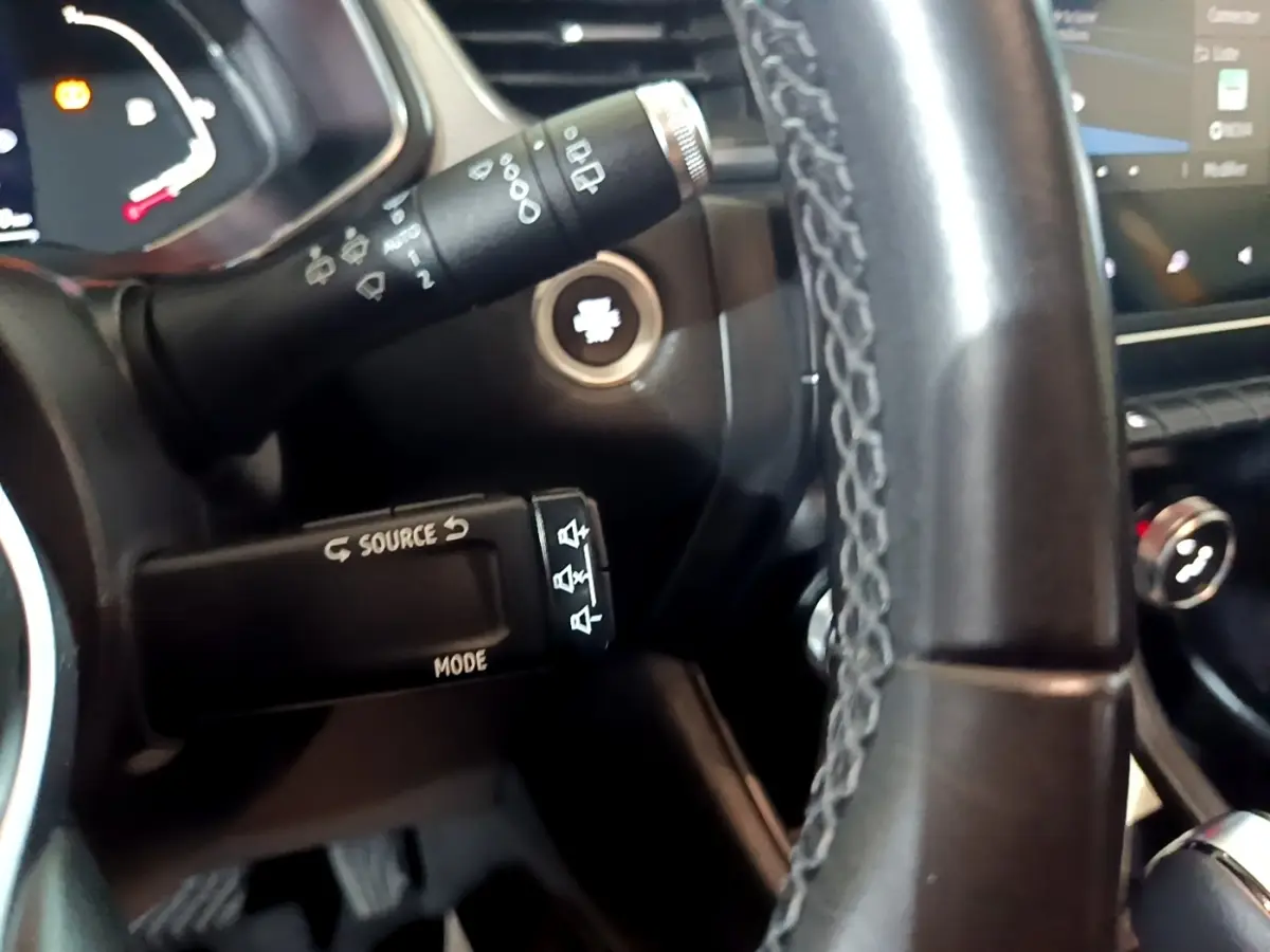 Gros plan sur le volant cuir et commandes multimédia du Renault Captur Intens jaune, tableau de bord et écran tactile visibles.